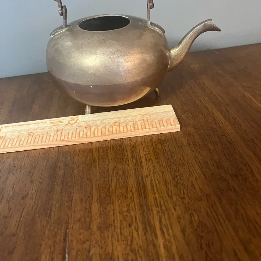 antique brass kettle with a wooden handle and three-legged base.